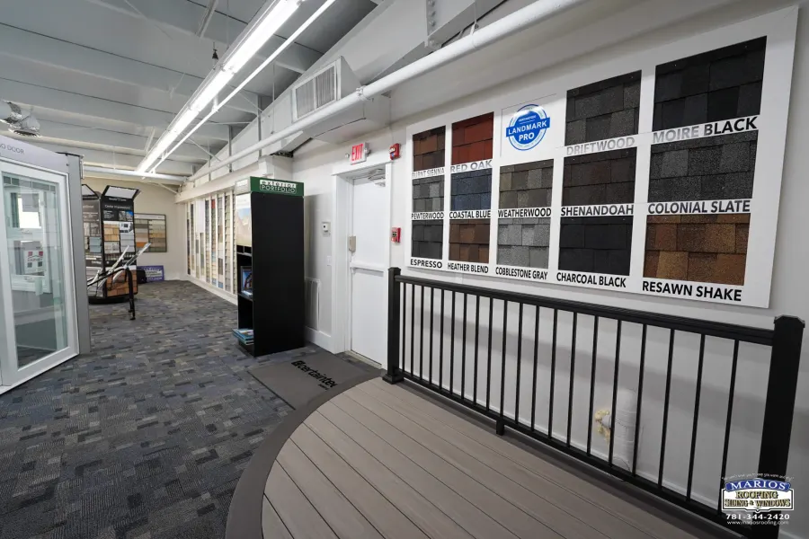 Wall of asphalt shingle color samples in the Marios showroom, with a decking display